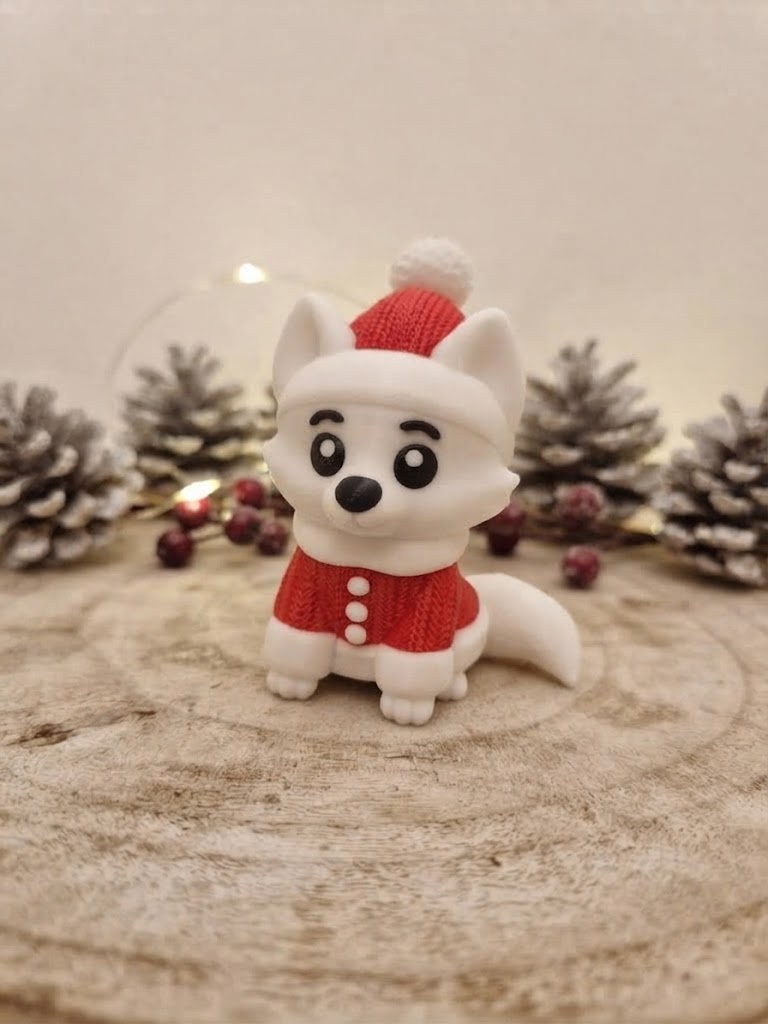 3D-gedruckter weißer Fuchs mit Weihnachtsmütze und rotem Oberteil vor Zapfen