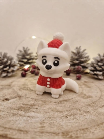 3D-gedruckter weißer Fuchs mit Weihnachtsmütze und rotem Oberteil vor Zapfen